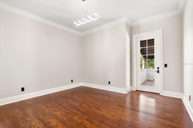 spare room featuring crown molding, dark hardwood / wood-style floors, and a chandelier