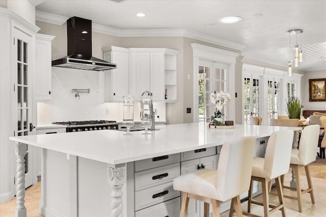 kitchen with french doors, white cabinetry, wall chimney exhaust hood, and a center island with sink