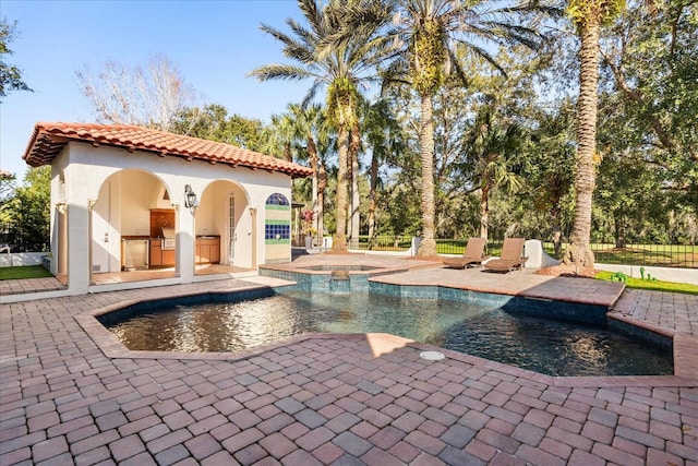 view of swimming pool featuring an in ground hot tub, an outdoor kitchen, and a patio area