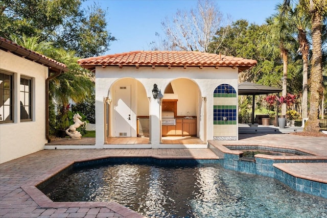 view of pool with an in ground hot tub, grilling area, exterior kitchen, and a patio