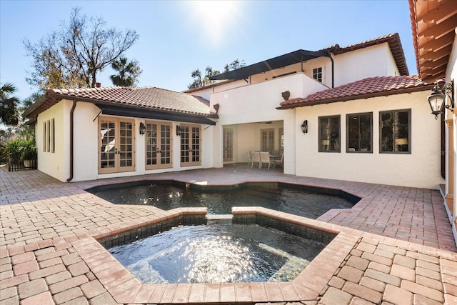 rear view of house featuring french doors, a swimming pool with hot tub, and a patio area