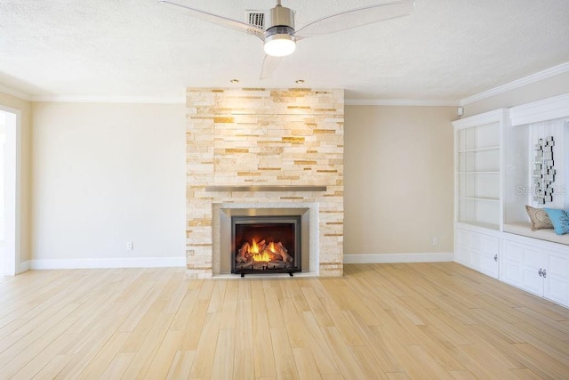 unfurnished living room with crown molding, a fireplace, light hardwood / wood-style floors, and a textured ceiling