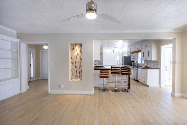 kitchen with ornamental molding, appliances with stainless steel finishes, and light wood-type flooring