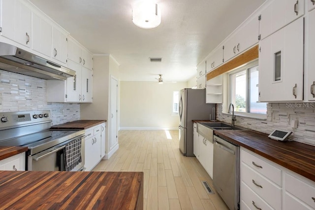 kitchen featuring butcher block counters, sink, white cabinetry, ceiling fan, and stainless steel appliances