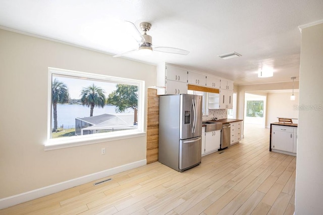 kitchen with appliances with stainless steel finishes, a wealth of natural light, decorative backsplash, and white cabinets