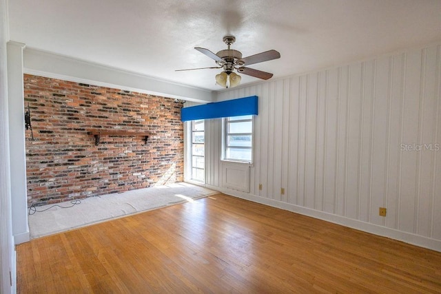 spare room with hardwood / wood-style flooring, ceiling fan, and brick wall