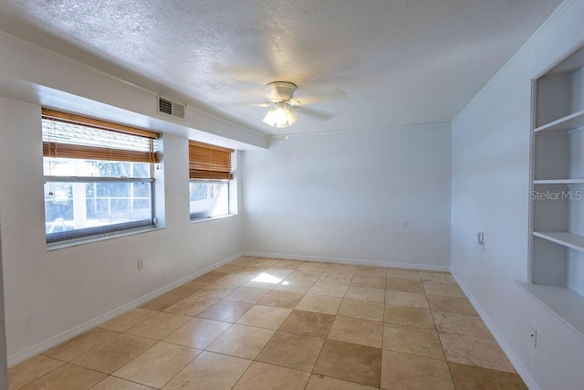 tiled spare room with built in shelves, ceiling fan, and a textured ceiling