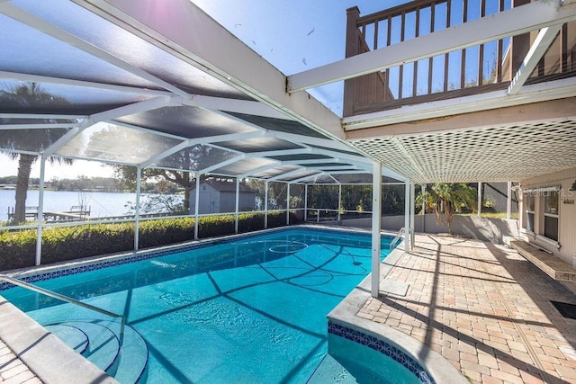 view of pool featuring a lanai, a water view, and a storage shed