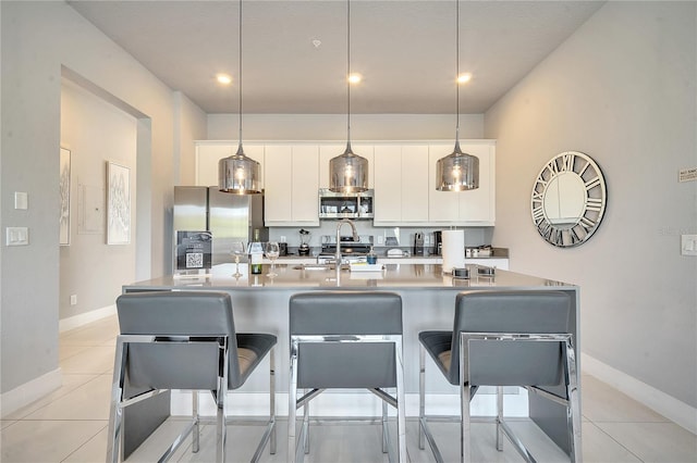 kitchen featuring appliances with stainless steel finishes, decorative light fixtures, a breakfast bar, and white cabinets