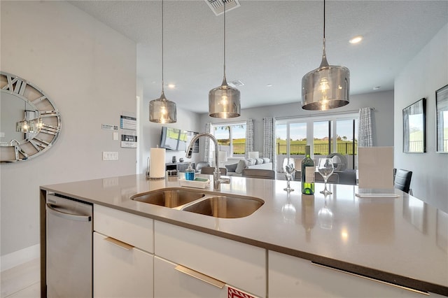 kitchen featuring pendant lighting, sink, white cabinets, stainless steel dishwasher, and plenty of natural light