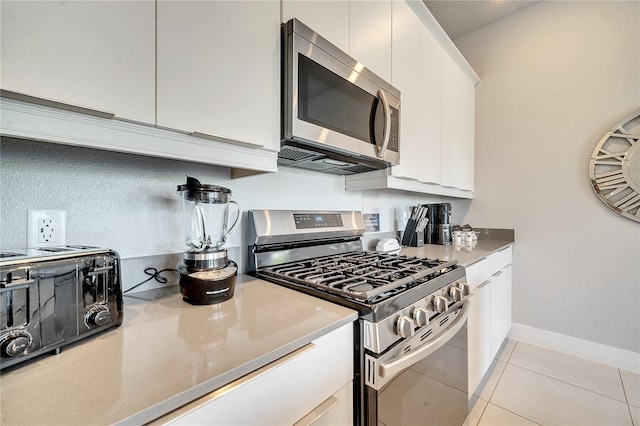 kitchen with stainless steel appliances, light tile patterned floors, and white cabinets