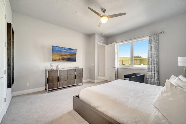 carpeted bedroom with ceiling fan and a textured ceiling