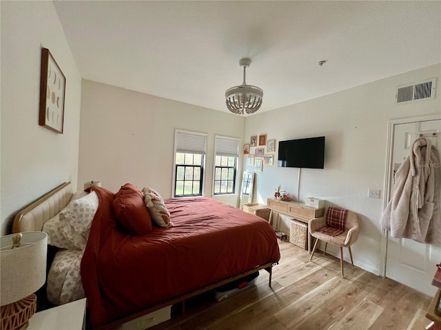 bedroom with a chandelier and light hardwood / wood-style flooring