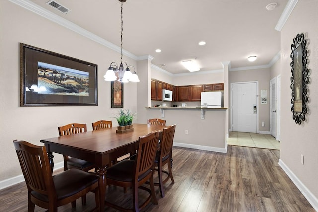 dining area featuring ornamental molding, an inviting chandelier, and dark hardwood / wood-style flooring