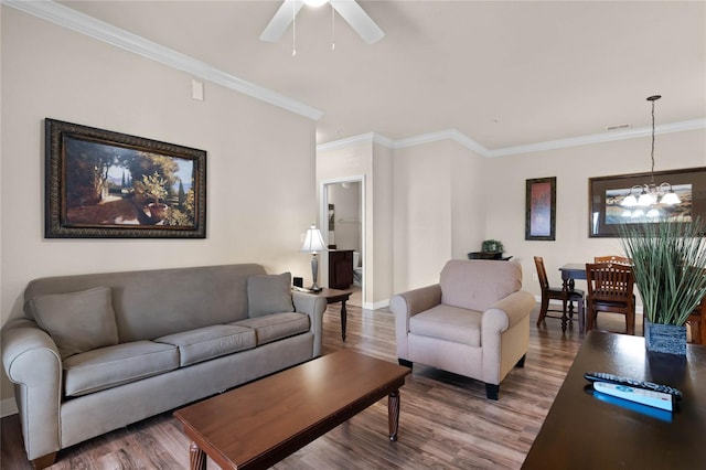 living room with hardwood / wood-style flooring, ornamental molding, and ceiling fan with notable chandelier