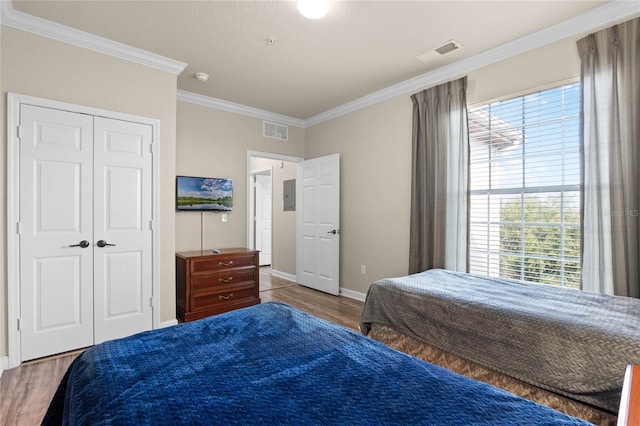 bedroom with ornamental molding, hardwood / wood-style floors, electric panel, and a closet