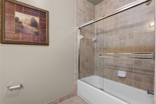 bathroom with bath / shower combo with glass door and tile patterned floors