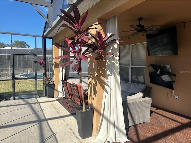 view of patio / terrace featuring ceiling fan and glass enclosure