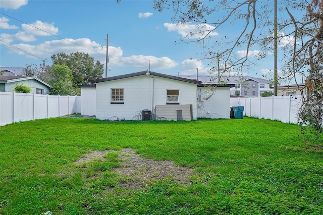 rear view of house featuring central AC unit and a lawn