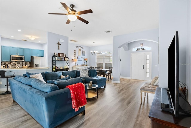 living room with ceiling fan with notable chandelier and light wood-type flooring