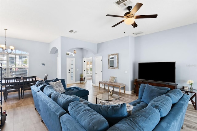 living room featuring ceiling fan with notable chandelier and light hardwood / wood-style floors