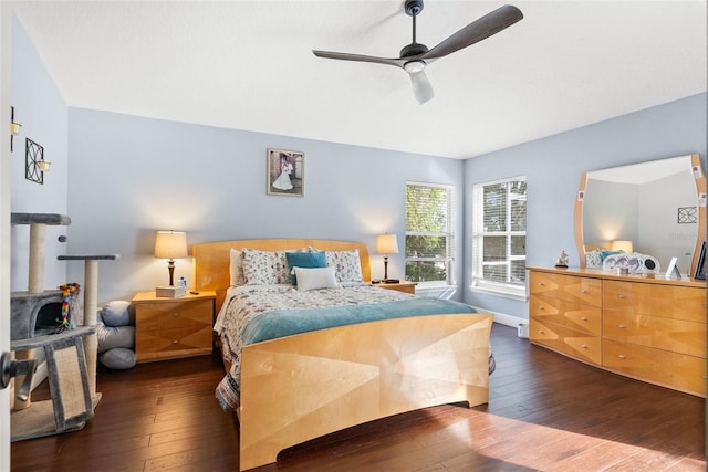 bedroom with ceiling fan, dark hardwood / wood-style flooring, and a wood stove