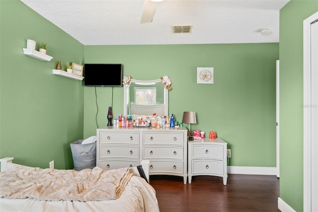 bedroom with ceiling fan, dark hardwood / wood-style flooring, and a textured ceiling