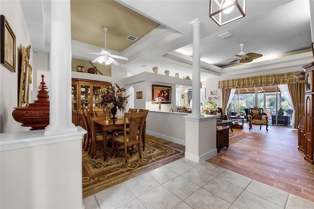 dining area with a tray ceiling, decorative columns, and ceiling fan