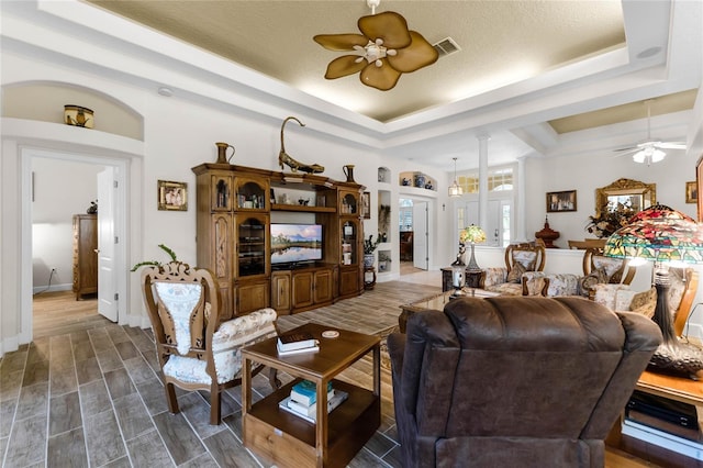 living room featuring a raised ceiling and ceiling fan