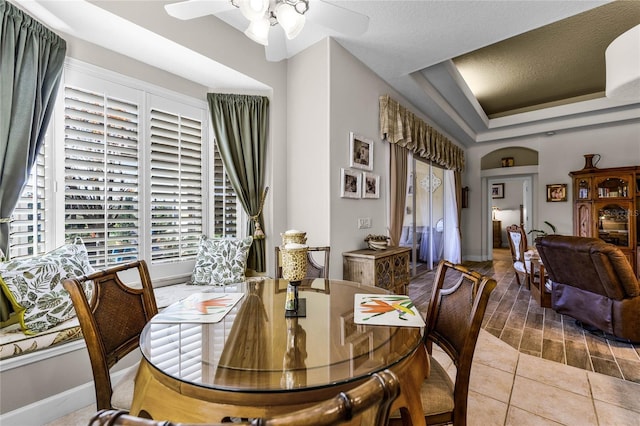 dining area featuring light tile patterned flooring, ceiling fan, and a tray ceiling