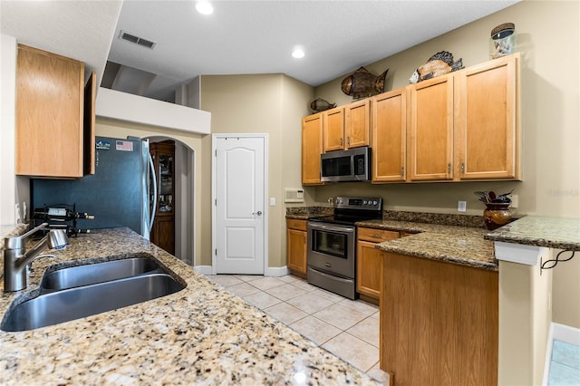 kitchen featuring light tile patterned flooring, sink, stone countertops, kitchen peninsula, and stainless steel appliances