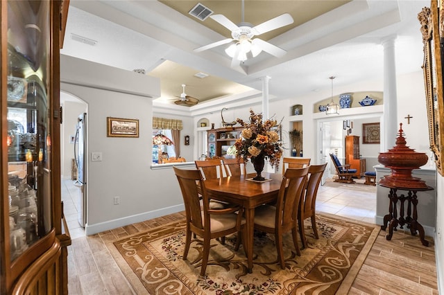 dining room with a healthy amount of sunlight, decorative columns, a raised ceiling, and ceiling fan