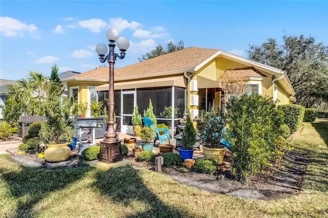 back of property with a lawn, a sunroom, and a hot tub