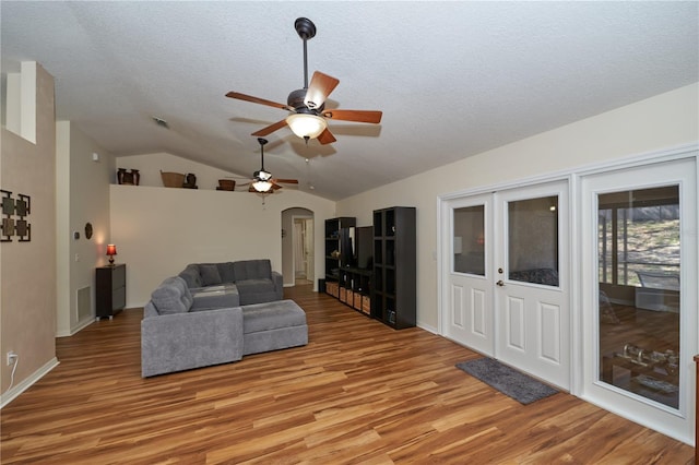 living room featuring ceiling fan, vaulted ceiling, light hardwood / wood-style flooring, and a textured ceiling