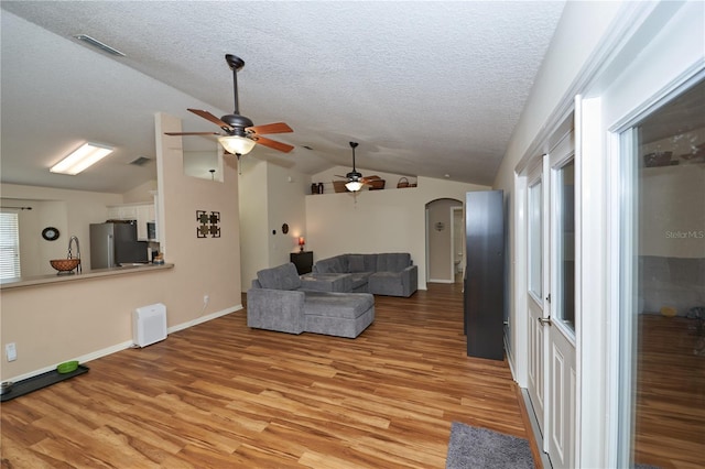 living room with light hardwood / wood-style floors, vaulted ceiling, and a wealth of natural light