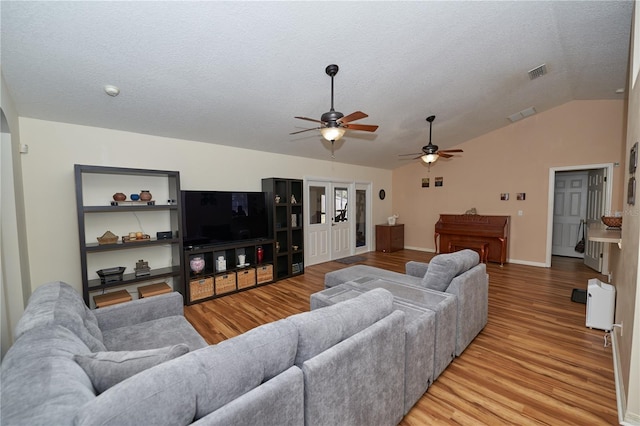 living room with ceiling fan, wood-type flooring, a textured ceiling, and vaulted ceiling