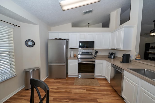 kitchen with stainless steel appliances, white cabinets, ceiling fan, and light hardwood / wood-style flooring