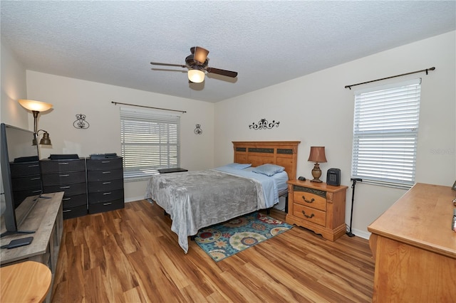 bedroom with hardwood / wood-style floors, a textured ceiling, and ceiling fan