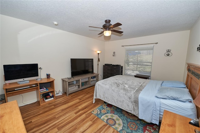 bedroom featuring ceiling fan, a textured ceiling, and light wood-type flooring