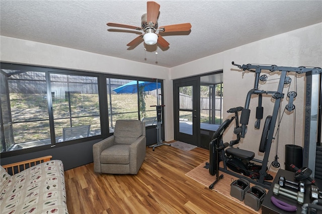 exercise area featuring hardwood / wood-style floors, french doors, a textured ceiling, and ceiling fan