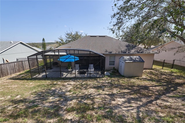 rear view of property with a shed, a patio, and glass enclosure