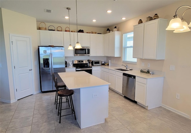 kitchen with a kitchen island, appliances with stainless steel finishes, sink, and pendant lighting