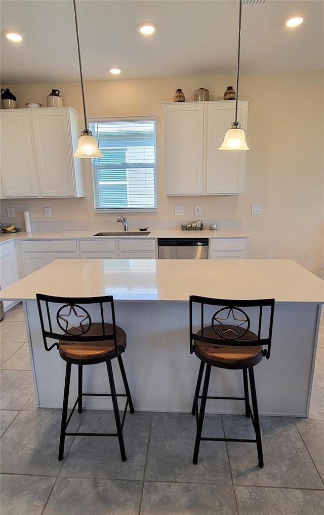 kitchen with a breakfast bar, dishwasher, white cabinetry, hanging light fixtures, and a kitchen island