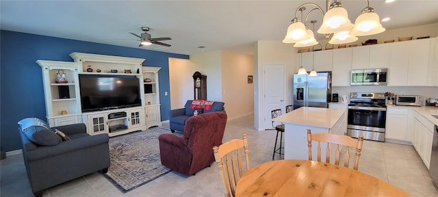 kitchen featuring a center island, light tile patterned floors, appliances with stainless steel finishes, pendant lighting, and white cabinets