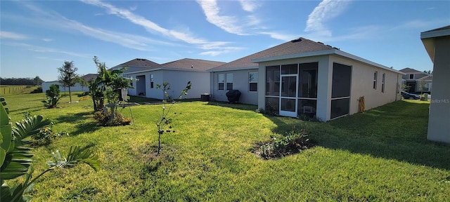 rear view of property with a sunroom and a lawn