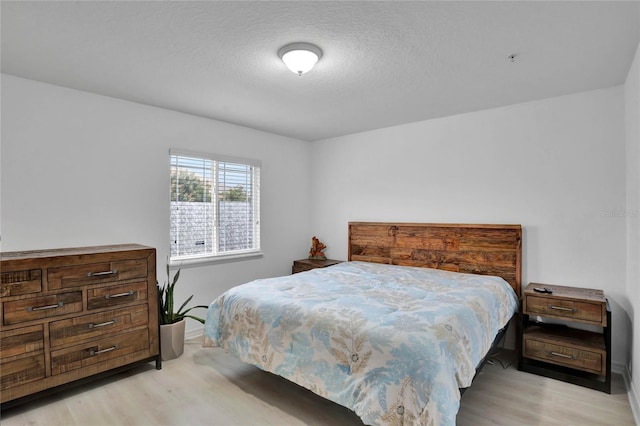 bedroom with a textured ceiling and light wood-type flooring