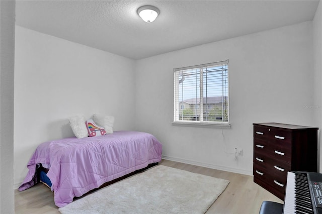 bedroom featuring light hardwood / wood-style floors and a textured ceiling