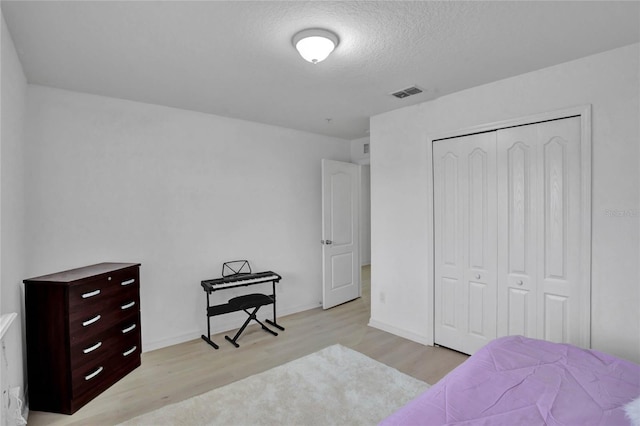 bedroom with light hardwood / wood-style flooring, a closet, and a textured ceiling