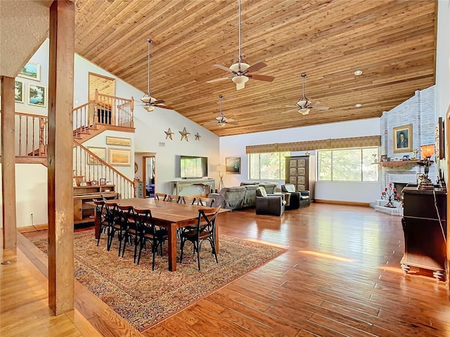 dining room featuring hardwood / wood-style flooring, high vaulted ceiling, wood ceiling, and a fireplace