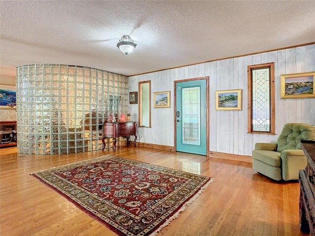 living area with ornamental molding, hardwood / wood-style floors, and a textured ceiling